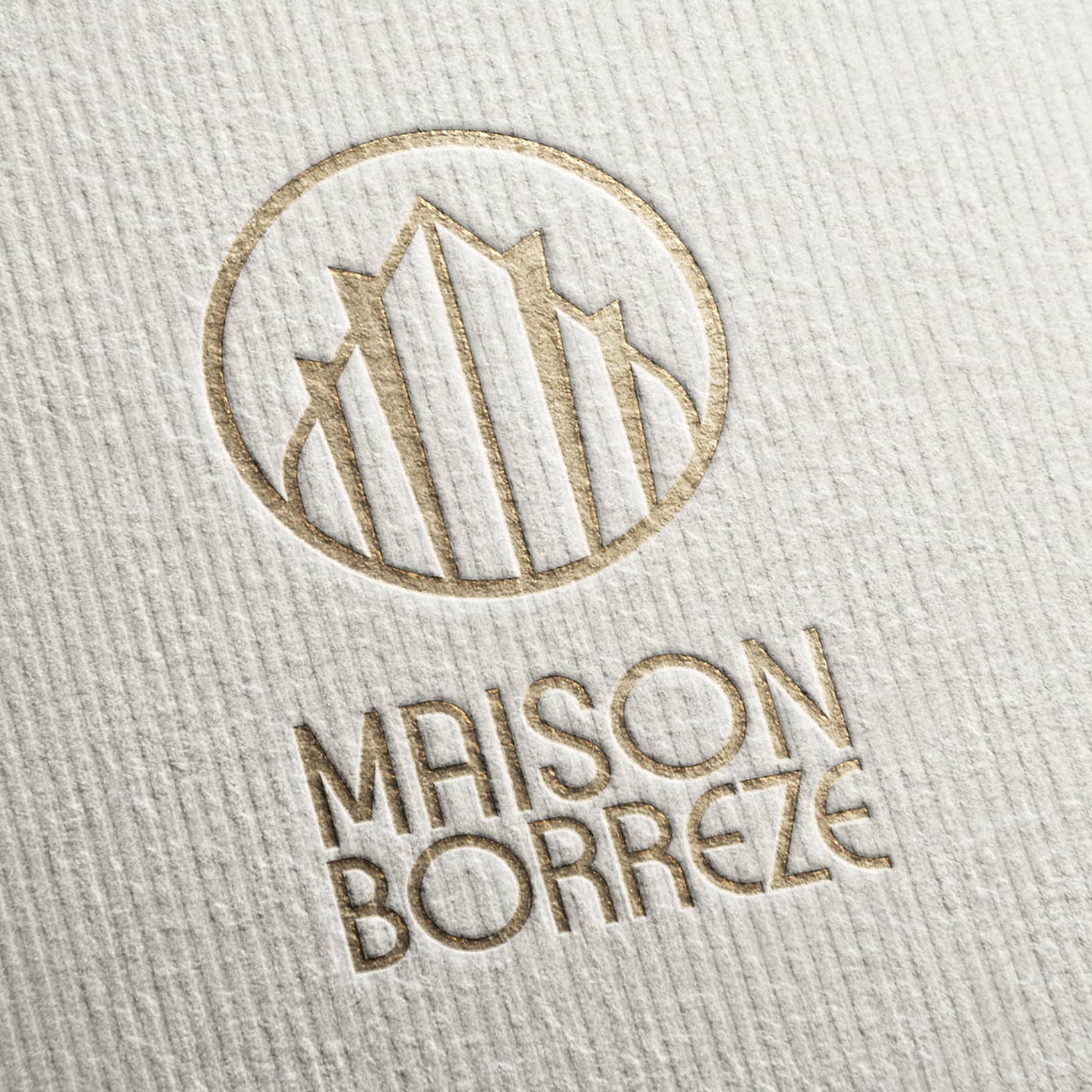 Logo doré Maison Borrezé embossé sur papier.