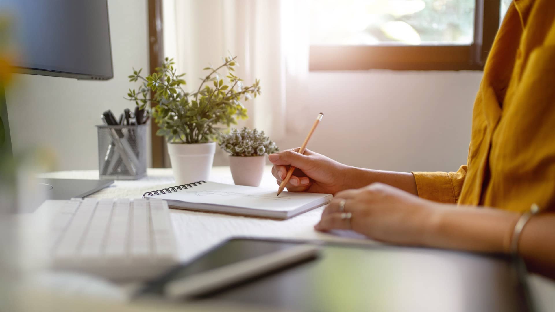 Personne écrivant dans un cahier, plantes en arrière-plan - agence de communication montpellier – Diadao
