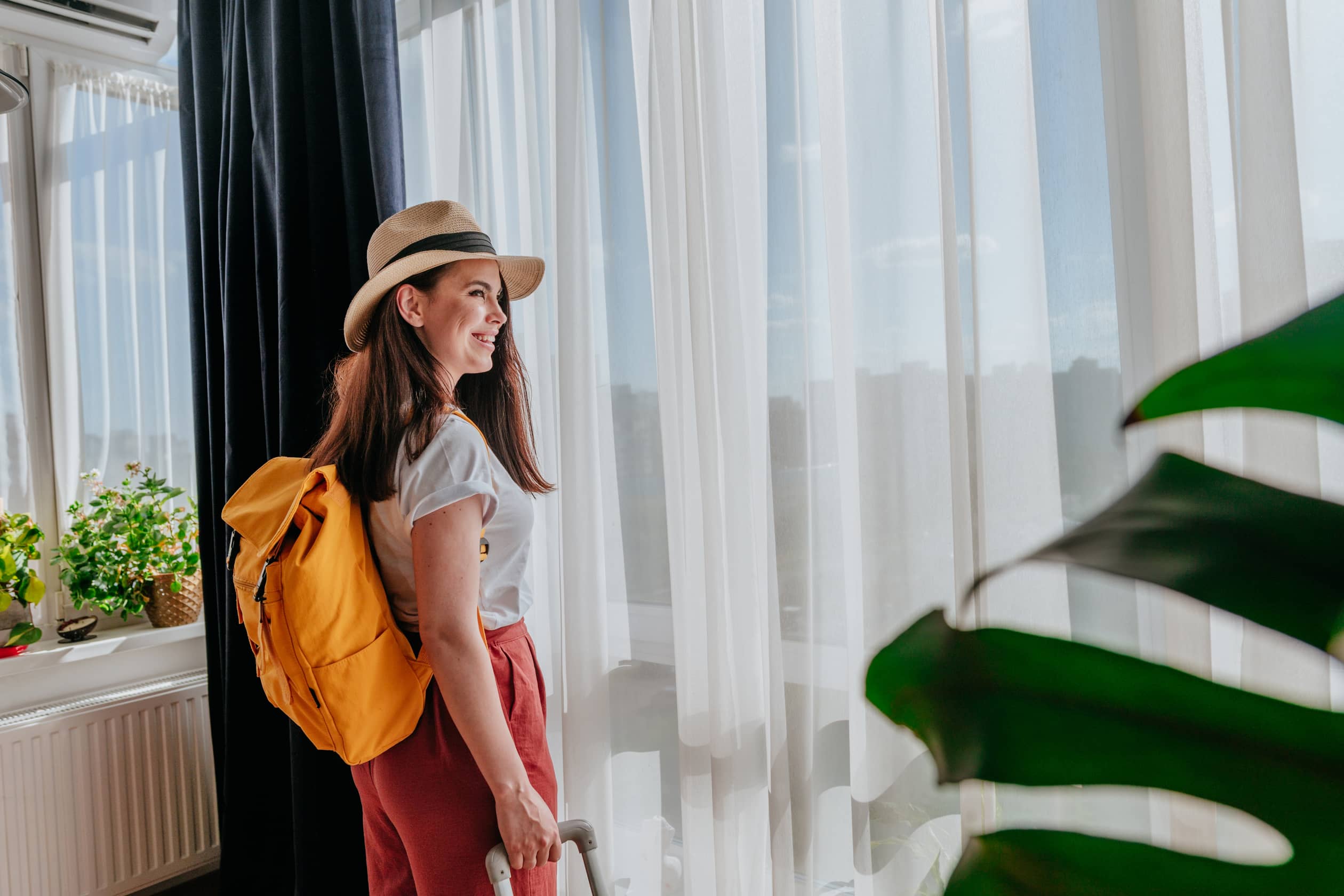back view of young woman looking out the window enjoying new city view